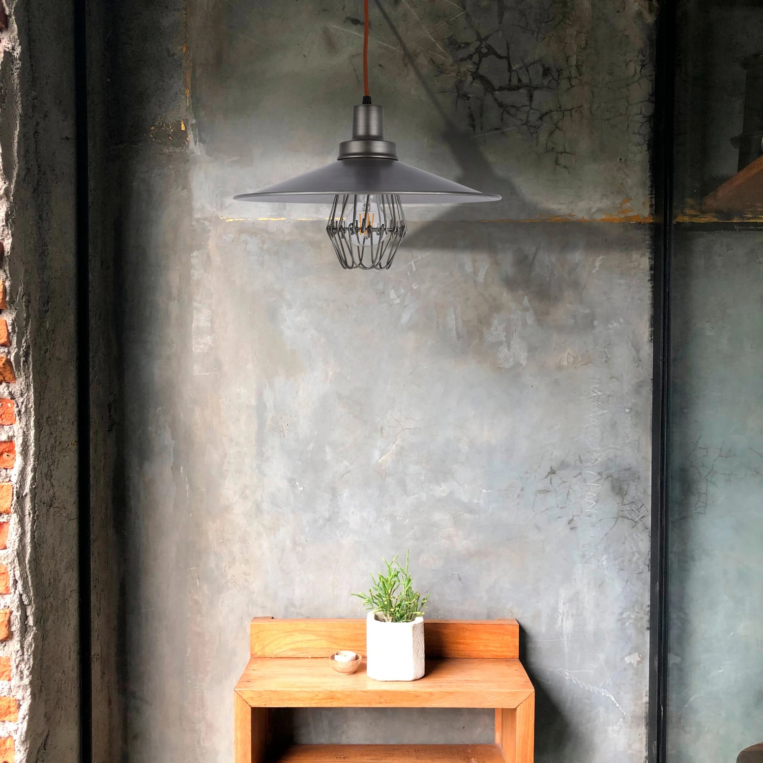 Industrial-style pendant light with a grey shade and cage, casting a soft, ambient glow. A modern statement piece for any room.