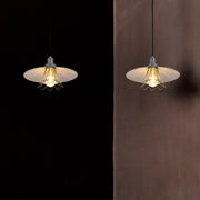 Two industrial pendant lights with metal shades and filament bulbs provide a warm, inviting glow against contrasting dark and neutral backgrounds.