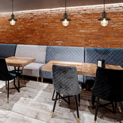 Rustic industrial pendant lights illuminate a cosy restaurant with exposed brick and plush quilted seating.