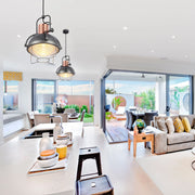 Industrial-style pendant lights hang above a kitchen island, adding a touch of modern charm to this bright, open-plan living space.