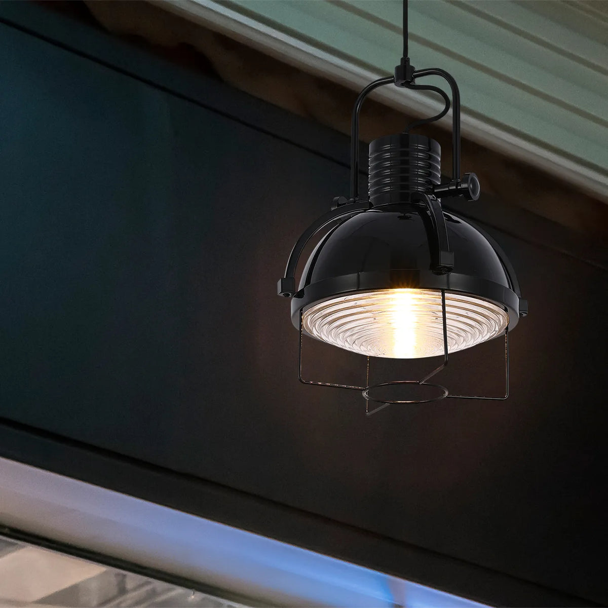 A black industrial-style pendant light with a ribbed glass shade emits a warm, inviting glow.