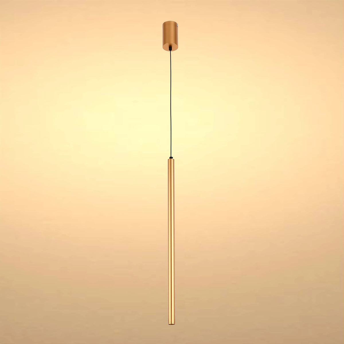 A modern, minimalist gold pendant light fixture with a long, slender cylindrical shade suspended from a black cable.