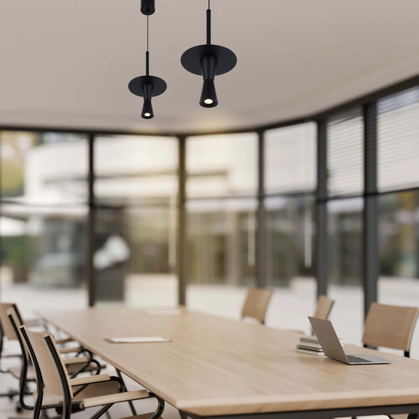 Contemporary black spotlights hang above a boardroom table. The lights have a sleek, minimalist design.