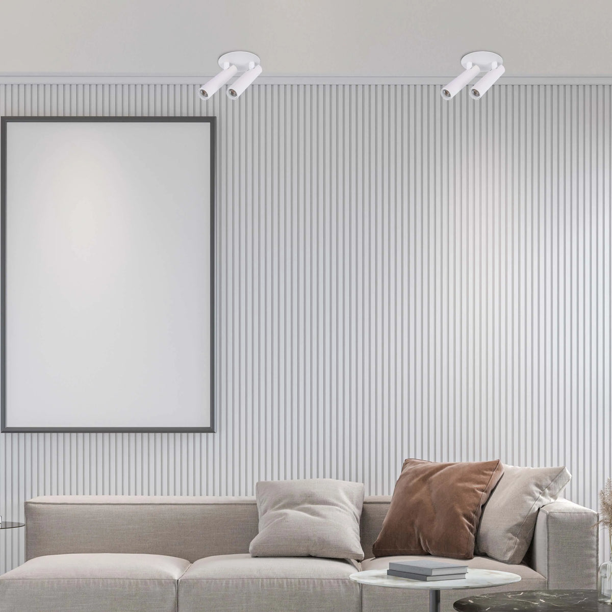 Minimalist white spotlights illuminate a living room with a blank framed poster above a modern sofa and side tables.