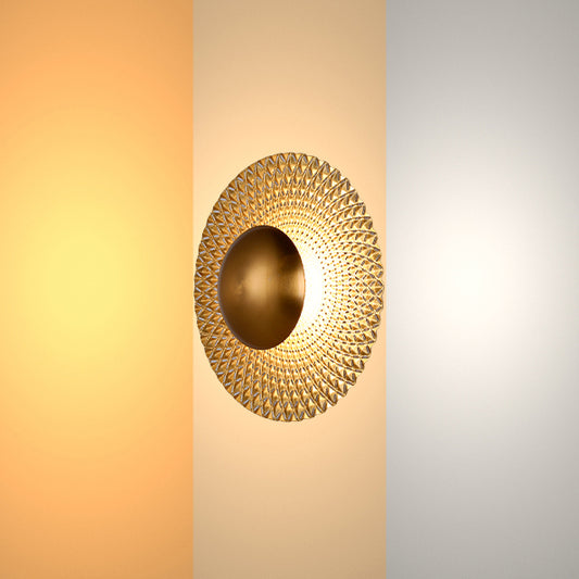A gold wall light with a round, textured shade, evenly lit with a soft, diffused glow.