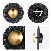 A decorative wall light with a gold globe centre, set against a black, geometric patterned shade.