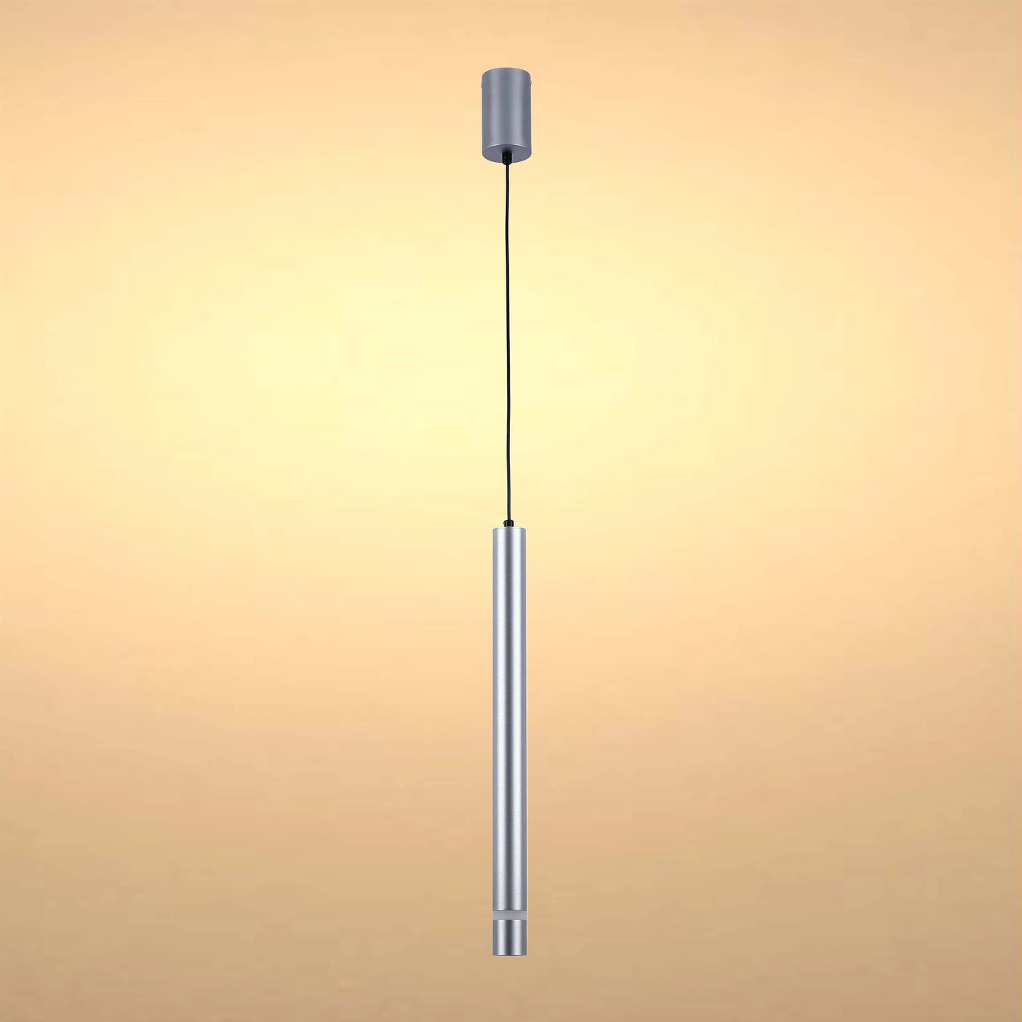A cylindrical, silver pendant light hangs from a black cable, softly lit against a warm, neutral background.