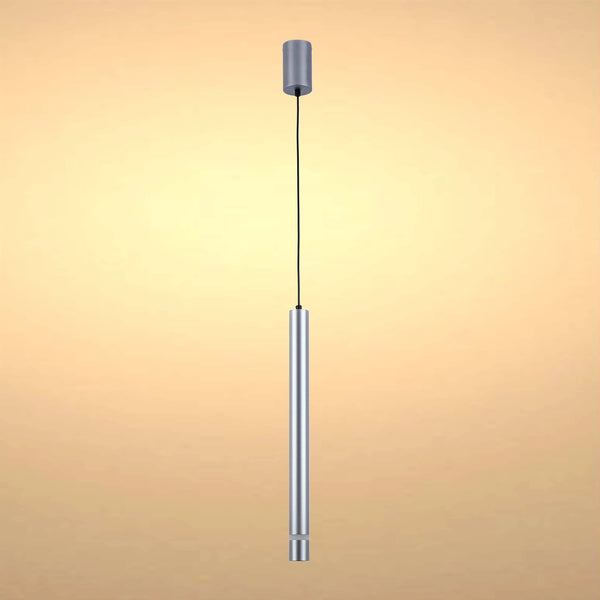 A cylindrical, silver pendant light hangs from a black cable, softly lit against a warm, neutral background.