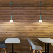 Two green pendant lights hang from the ceiling, illuminating a stylish cafe setting with a warm and inviting atmosphere.