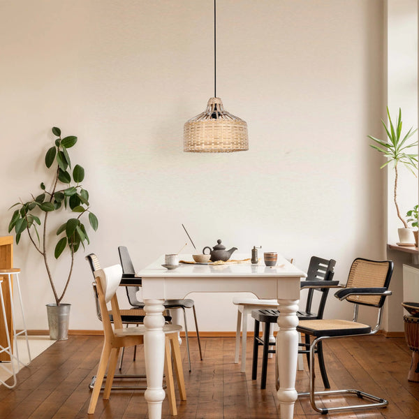 Wicker pendant light hanging above a dining table, casting a warm, ambient glow. Natural light also fills the room.