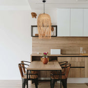 A rattan pendant light hangs above a wooden table and chairs, creating a warm and inviting atmosphere.