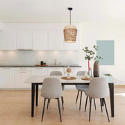 A dining room is illuminated by a woven pendant light, suspended above a table with modern chairs. Natural light streams in.
