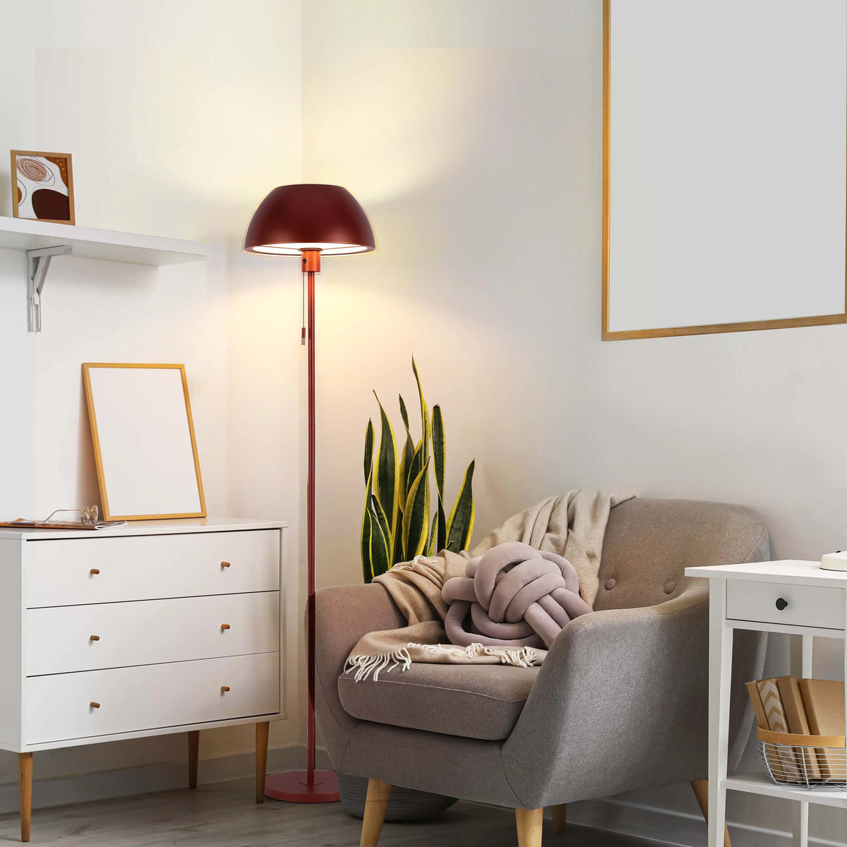 A red floor lamp illuminates a cosy reading nook, with warm light creating an inviting atmosphere in the neutral-toned room.