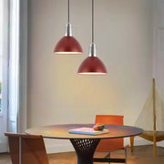 Two red dome pendant lights hang above a dining table, providing warm, inviting illumination. Modern design.