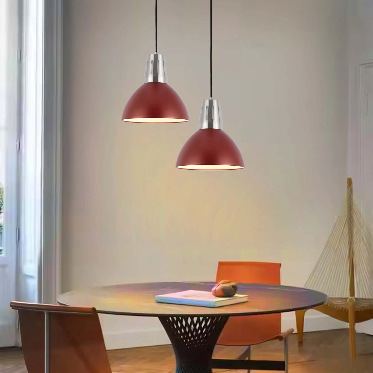 Two red dome pendant lights hang above a dining table, providing warm, inviting illumination. Modern design.