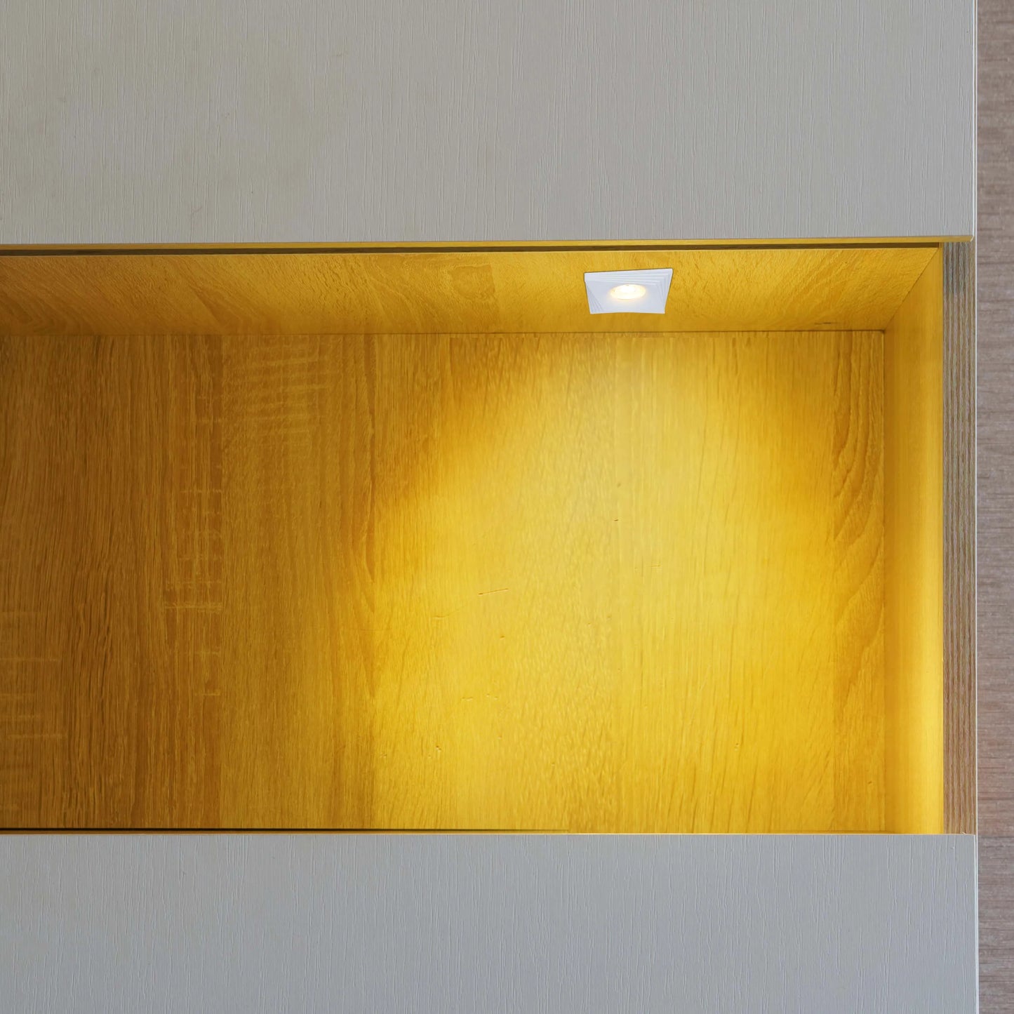 Warm, inviting light from a recessed spotlight illuminates a niche, creating a cosy and stylish display space.