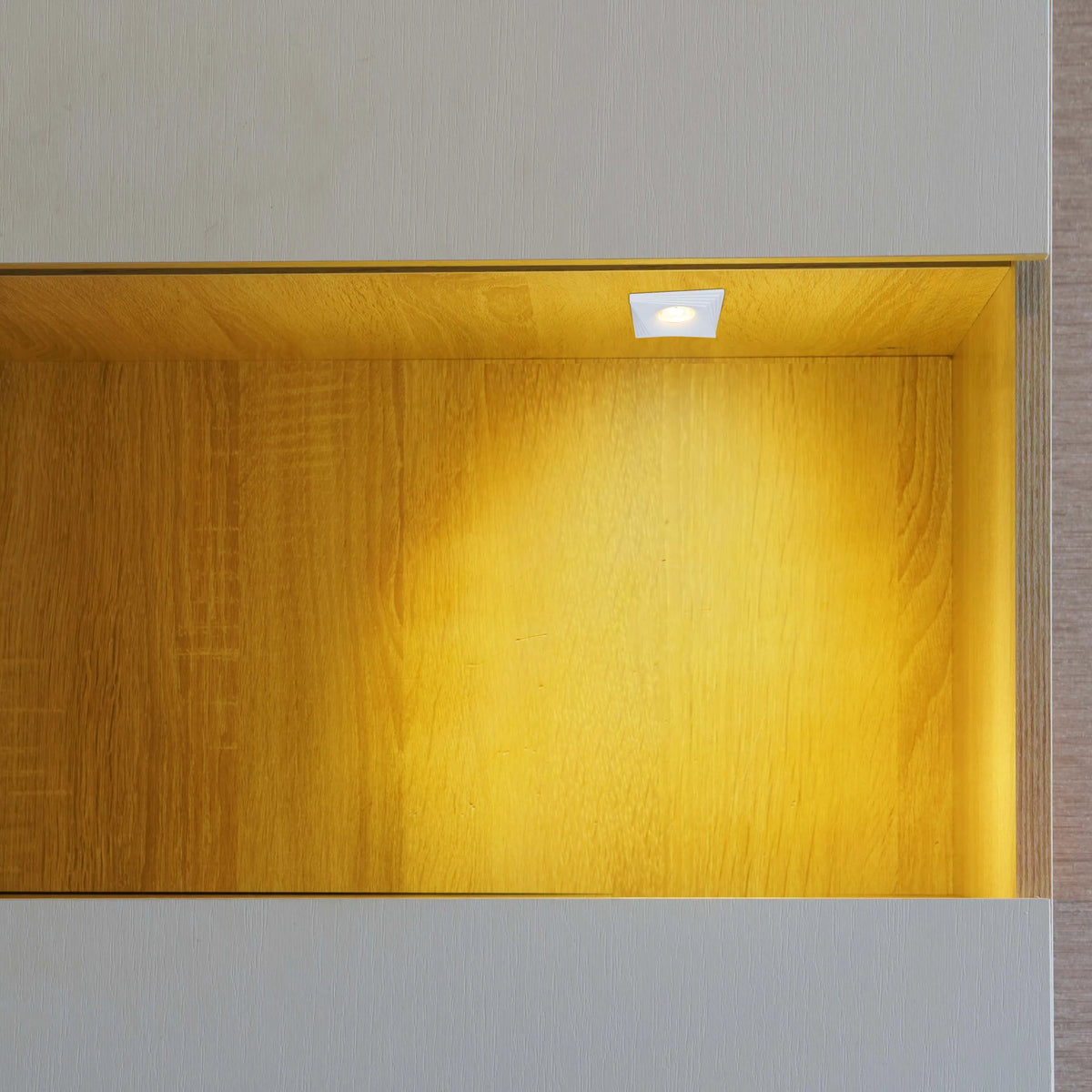 Warm, inviting light from a recessed spotlight illuminates a niche, creating a cosy and stylish display space.