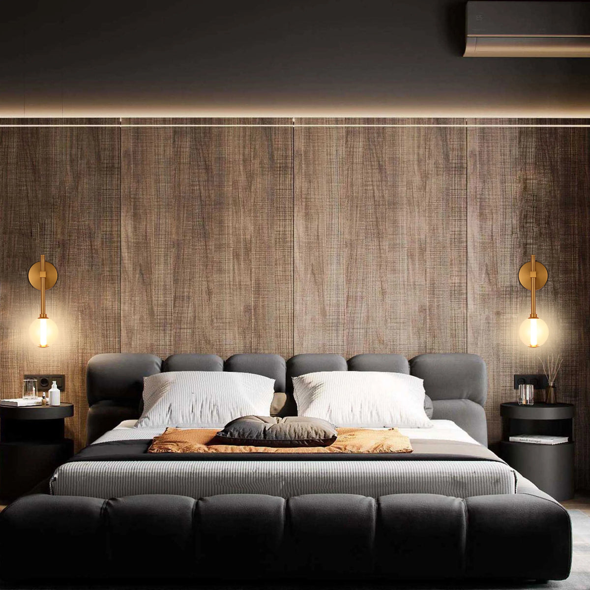 Bedroom with ambient lighting. Wall-mounted sconces flank a large, upholstered bed against a wood panelled wall.
