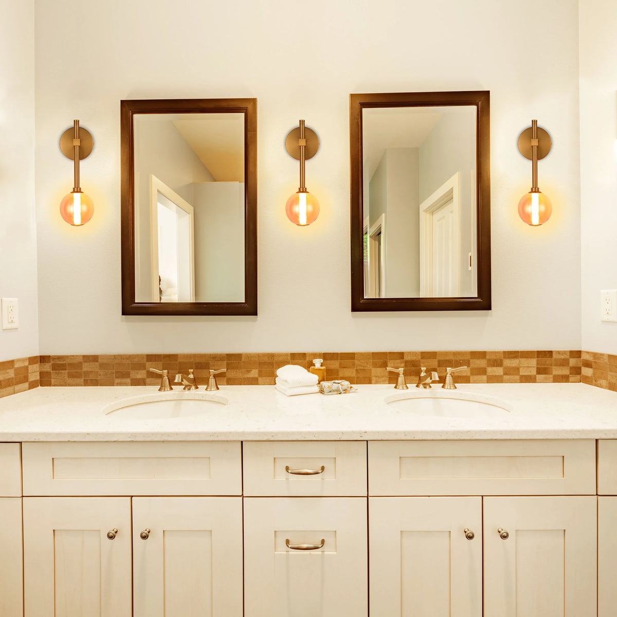 A bathroom with two brown-framed mirrors and three globe-shaped vanity lights.