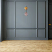 A contemporary wall light with a brass fixture and pink glass globe, adding a touch of elegance to the room's decor.