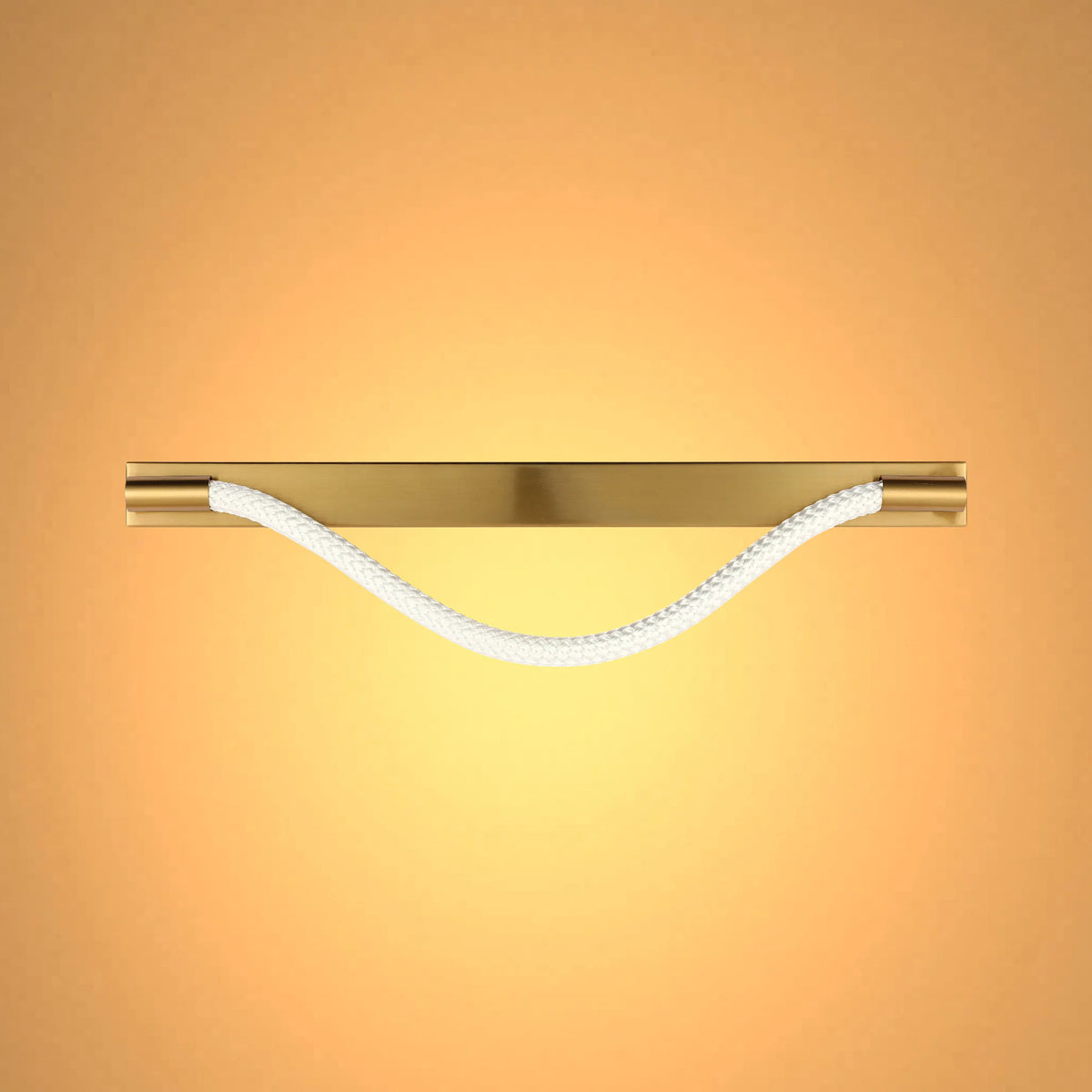 A modern light fitting with a gold fixture and a white rope element, casting a warm and inviting glow.