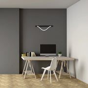 Modern desk setup featuring a sleek black pendant light with a white, curved rope accent, illuminating the workspace below.