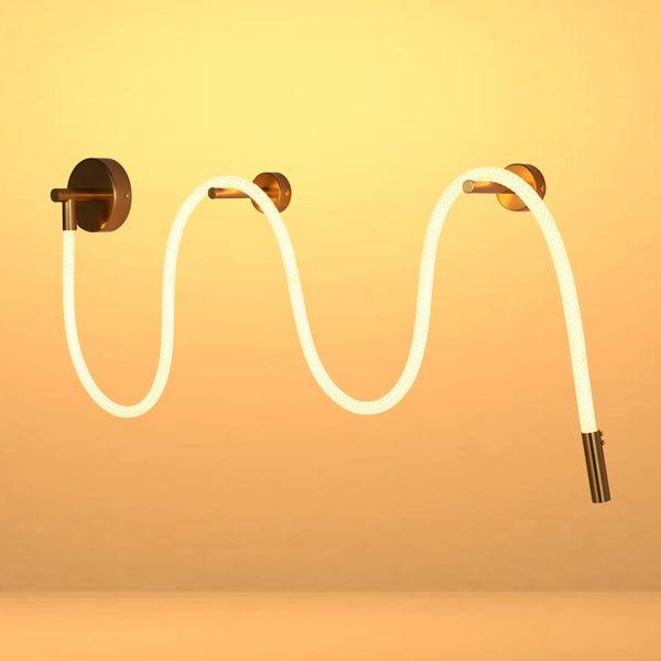 A modern, wavy wall light fixture with bronze fixings and a diffused, linear light source creates a warm, inviting ambiance.