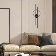Modern wall light with matte black finish and circular design, casting a soft, ambient glow on the beige wall.