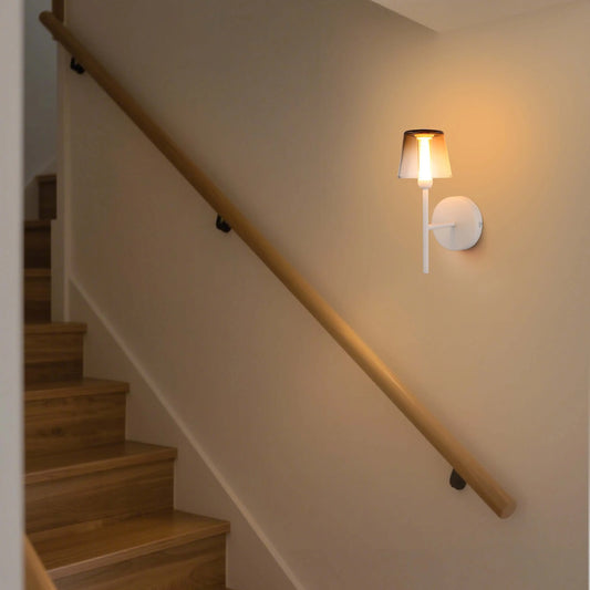 A wall-mounted light fixture illuminates a stairwell, offering a warm and inviting ambiance with its soft glow.