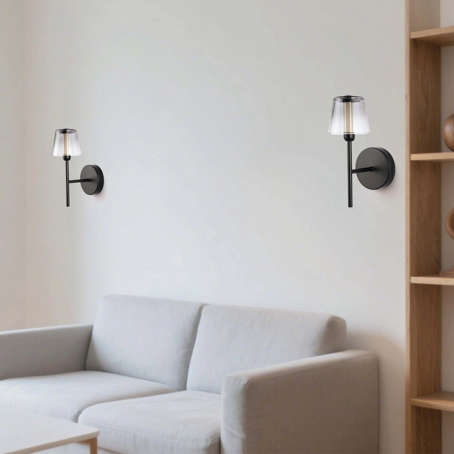 Two stylish black sconces with clear glass shades illuminate a neutral living room, showcasing modern wall lighting.