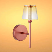 A copper-coloured wall light with a translucent amber-tinted shade, casting a soft, ambient glow.