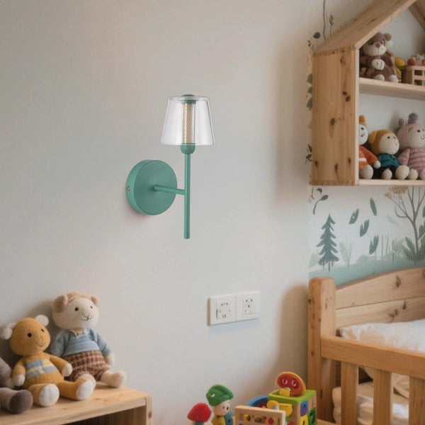 A green wall light with a clear shade illuminates this child's bedroom. Soft toys and a wooden bed frame complete the scene.