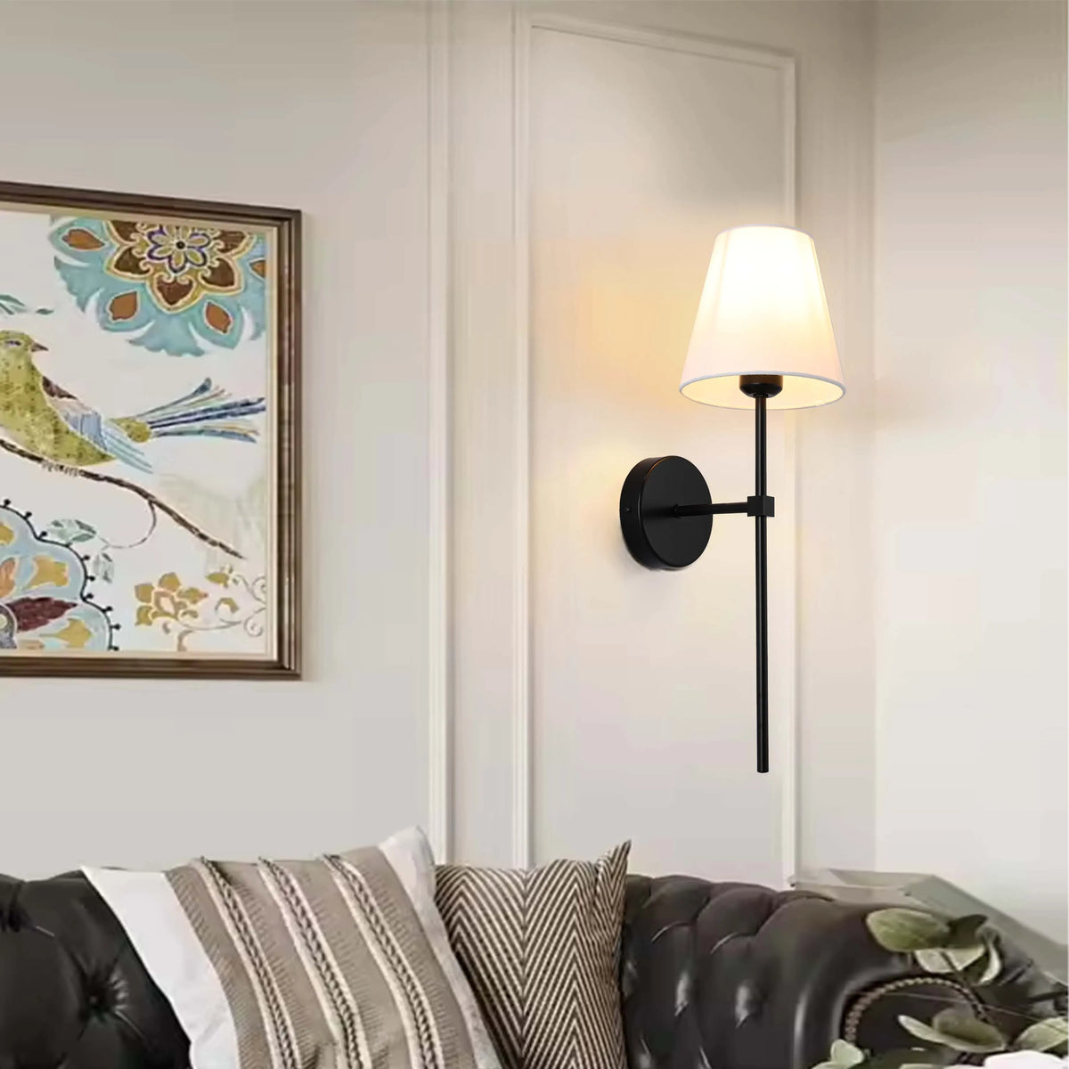A modern black sconce with a white drum shade provides ambient lighting in a stylish living room.