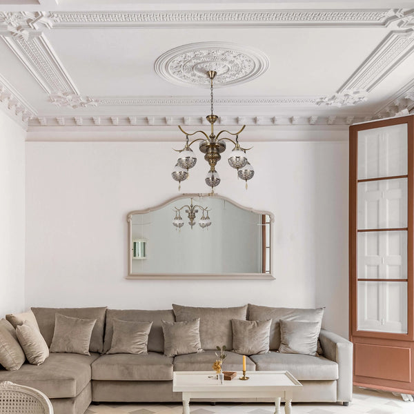 An ornate chandelier hangs from a decorative ceiling rose, providing ambient light to a sophisticated lounge setting.