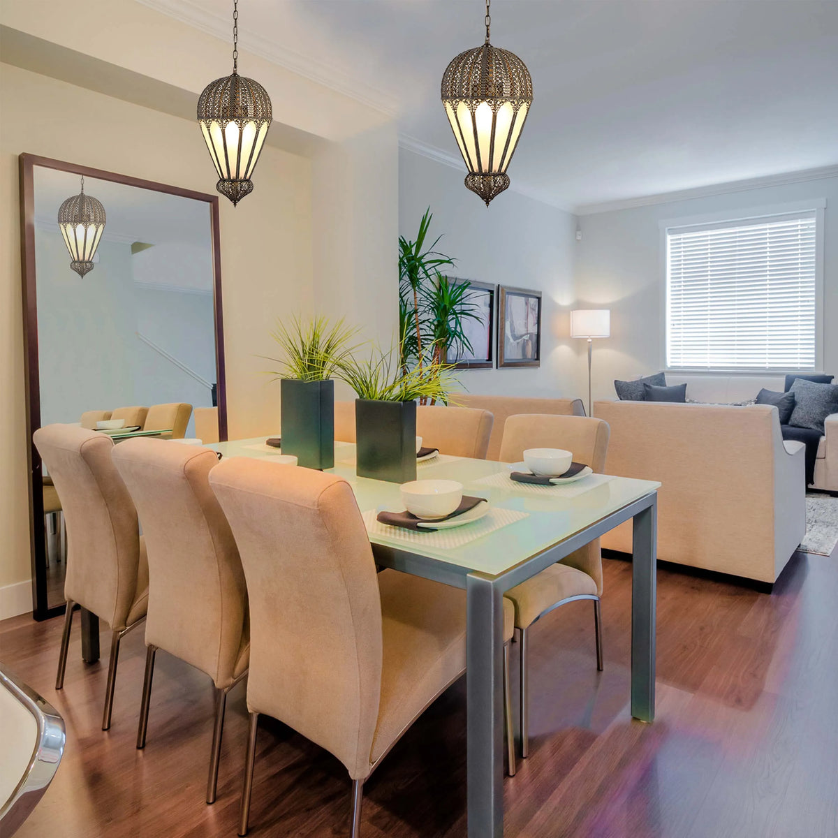 Ornate hanging lights illuminate a dining space with a modern glass table and neutral-toned chairs, creating a warm, inviting atmosphere.