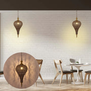Two intricate gold pendant lights cast patterned shadows on a white brick wall in a dining area, creating a warm, inviting atmosphere.