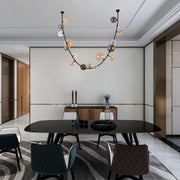 Statement chandelier with a curved black frame and contrasting glass spheres, adding a modern, eye-catching feature to the dining room.