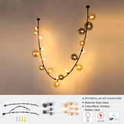 Statement pendant light with multiple glass orbs in smokey, amber and clear colours. Black steel frame.