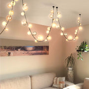 Contemporary bubble chandelier featuring globe lights strung along black wires, adding a warm and modern touch to the room.