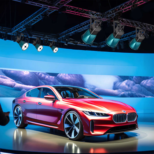 A striking display of stage lighting illuminates a sleek, red concept car. The blue hues give a high-tech feel to the scene.