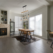 Statement pendant light with six Edison-style bulbs, hanging over a rustic dining table.