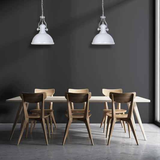 Two white pendant lights illuminate a dining table with wooden chairs. Natural light fills the room from a nearby window.