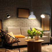 Cosy living room scene, lit by a pendant, wall and floor lamps. Warm lighting creates an inviting, atmospheric ambience.