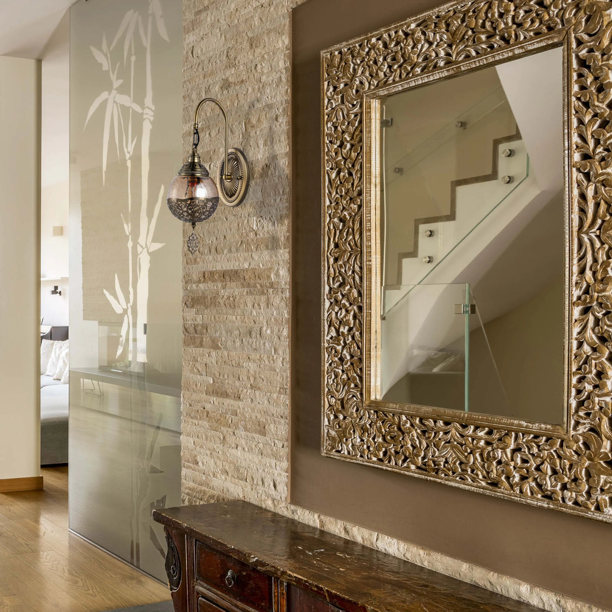 Ornate wall sconce and mirror create a warm glow, enhancing the textured wall. Stylish lighting.