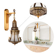 An ornate Moroccan style wall sconce with gold metalwork and frosted glass. A bathroom features the same light next to a mirror.