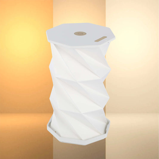 A modern, geometric lamp casts a soft glow. Its concertina design and minimalist style adds an elegant touch to any interior.