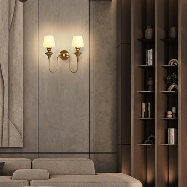 A wall mounted sconce with a polished brass finish and frosted glass shades creates warm, inviting ambient lighting.