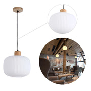 A stylish, modern pendant light with a textured, opaque shade and wooden cap. A warm, inviting glow adds ambience.