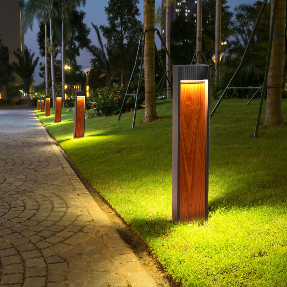 Modern bollard lights illuminate a paved walkway and lawn at night, creating a warm and inviting ambience.