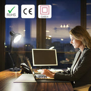 A desk with a lamp, laptop, monitor and phone, providing an office workspace.